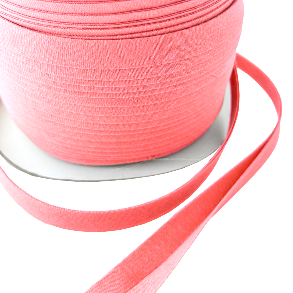 close up of the coral pink 1/2" double fold bias tape on a spool from Heit's Wholesale bulk sewing supply company