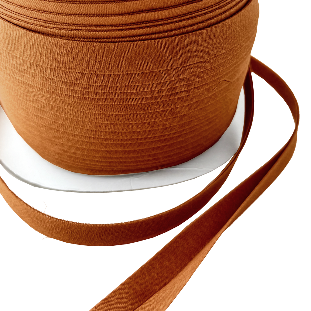 close up of the sandlewood 1/2" double fold bias tape on a spool from Heit's Wholesale bulk sewing supply company