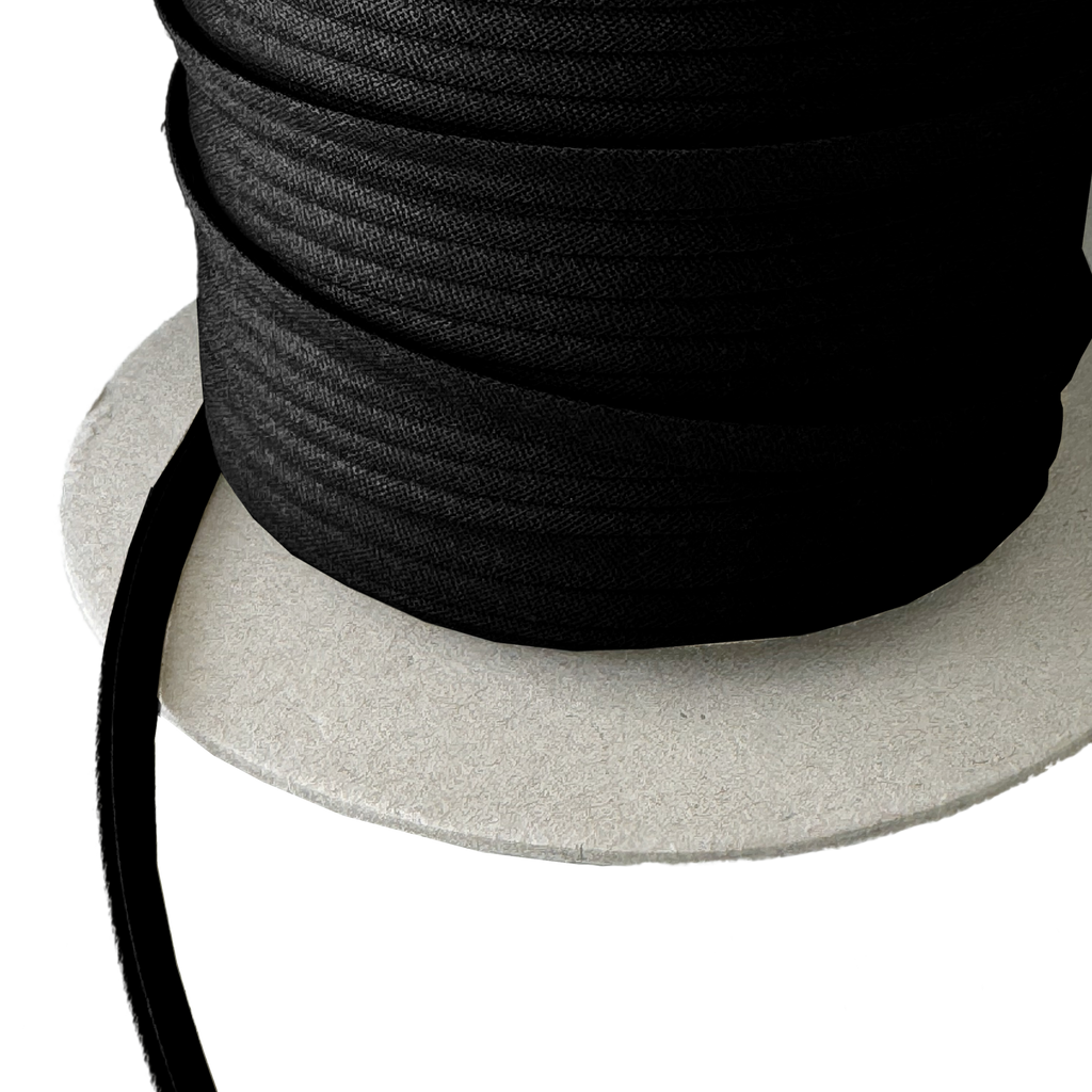 close up of the black 1/4" double fold bias tape on a spool from Heit's Wholesale bulk sewing supply company