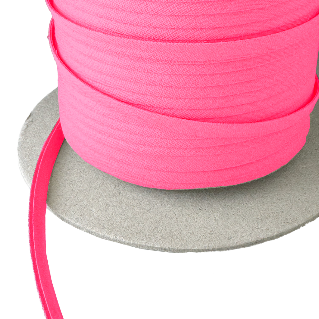 close up of the candy pink 1/4" double fold bias tape on a spool from Heit's Wholesale bulk sewing supply company