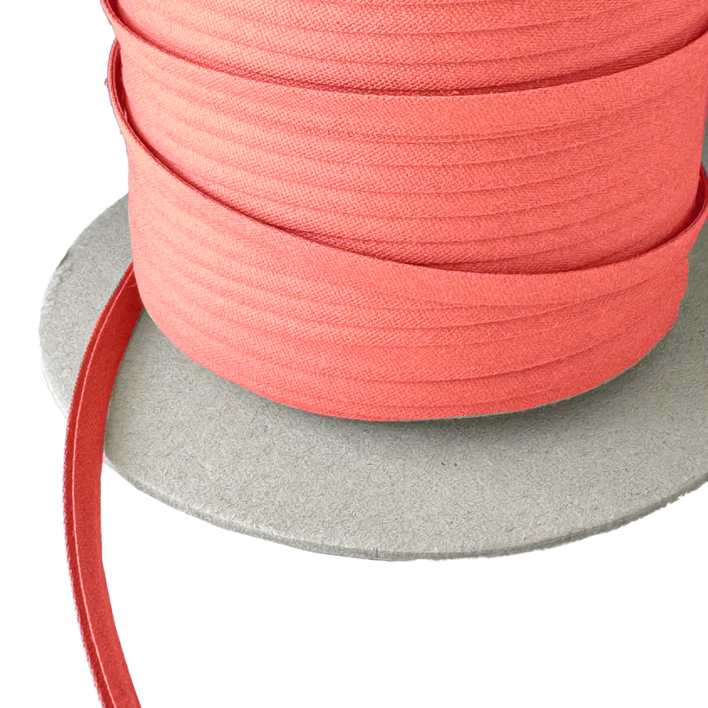 closer view of the coral 1/4" double fold bias tape on a spool from Heit's Wholesale bulk sewing supply company