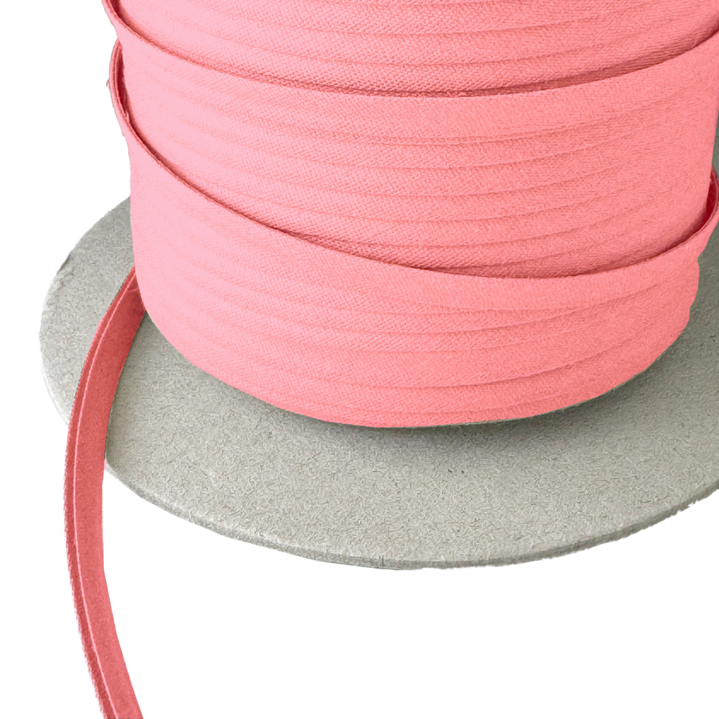 close up of the coral pink 1/4" double fold bias tape on a spool from Heit's Wholesale bulk sewing supply company