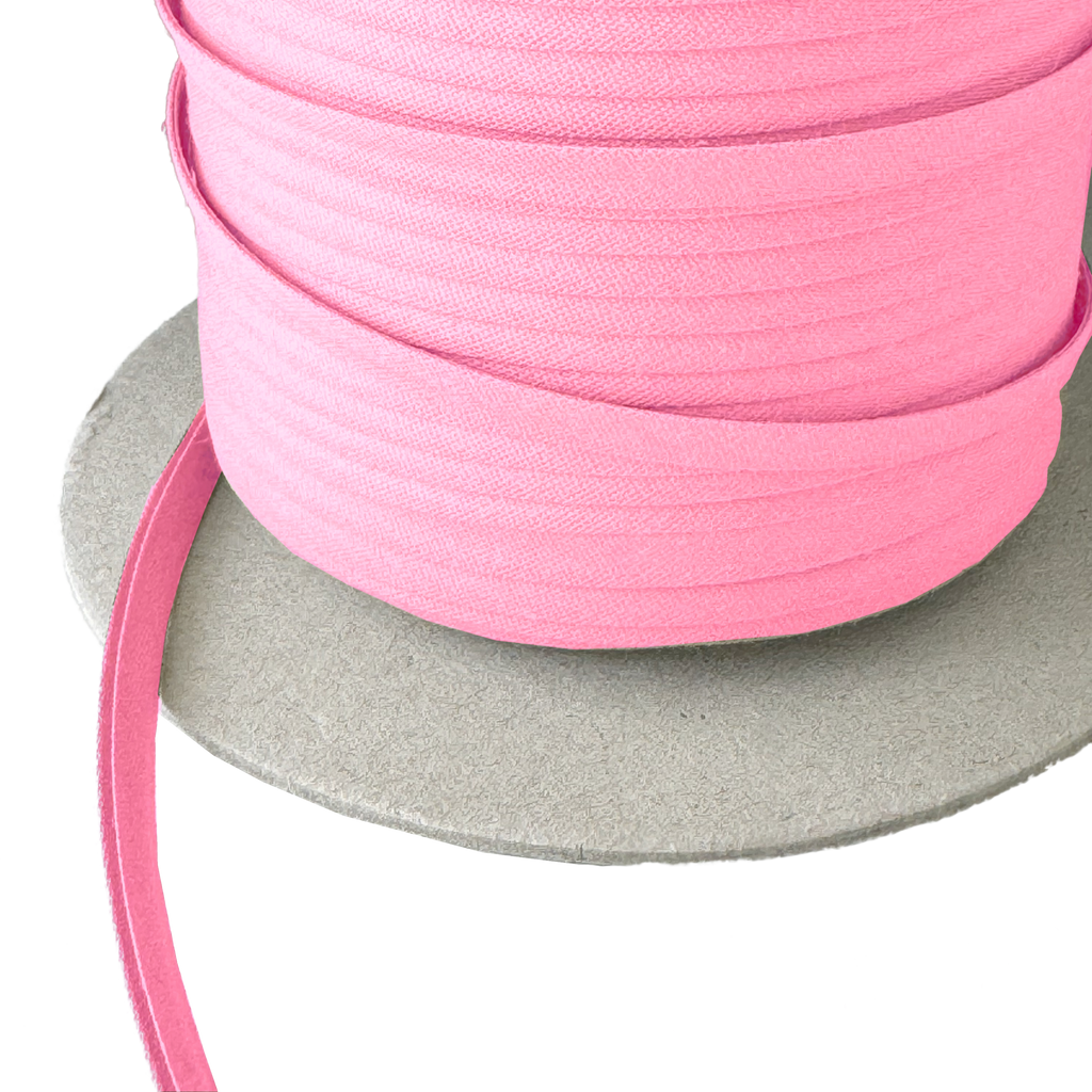 close up of the cotton candy pink 1/4" double fold bias tape on a spool from Heit's Wholesale bulk sewing supply company
