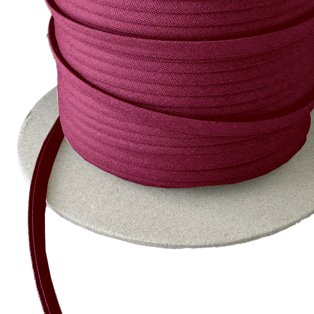 close up of the cranberry 1/4" double fold bias tape on a spool from Heit's Wholesale bulk sewing supply company