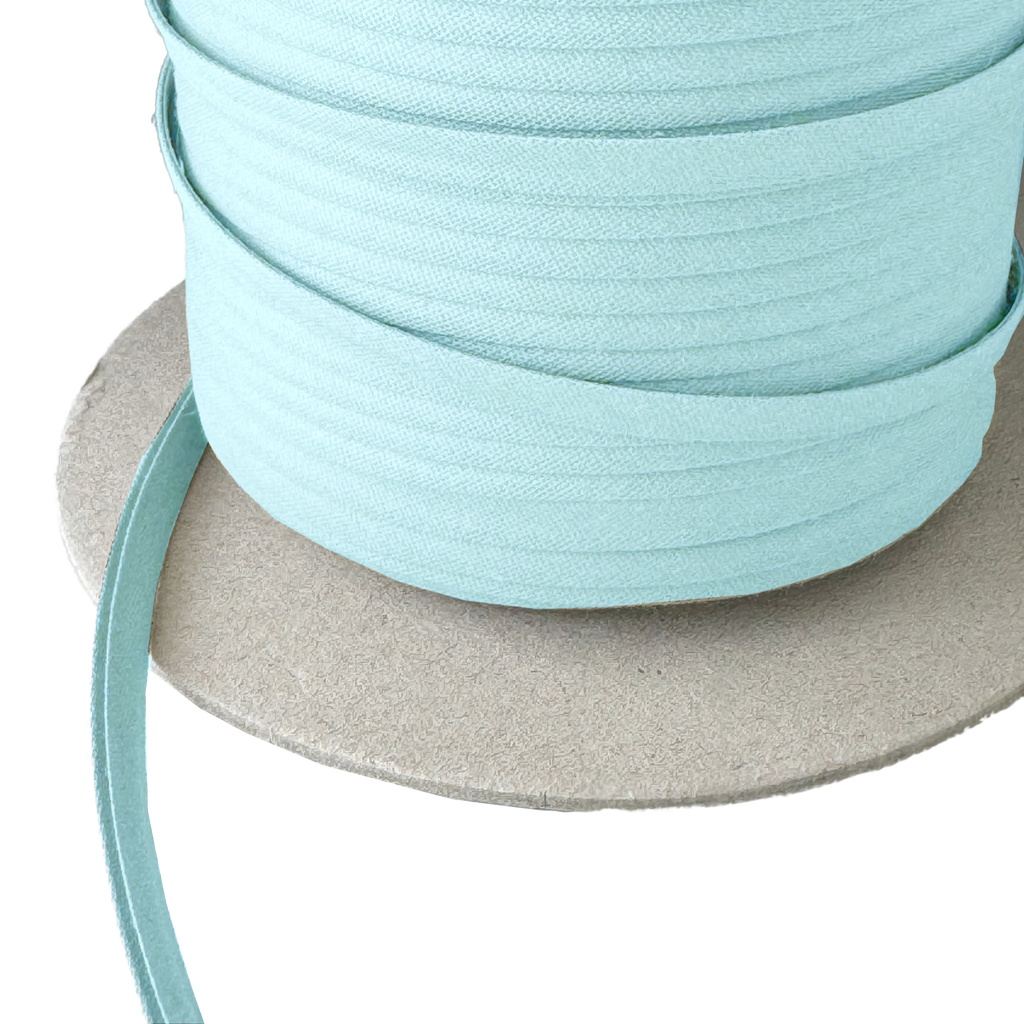 close up of the frost blue 1/4" double fold bias tape on a spool from Heit's Wholesale bulk sewing supply company