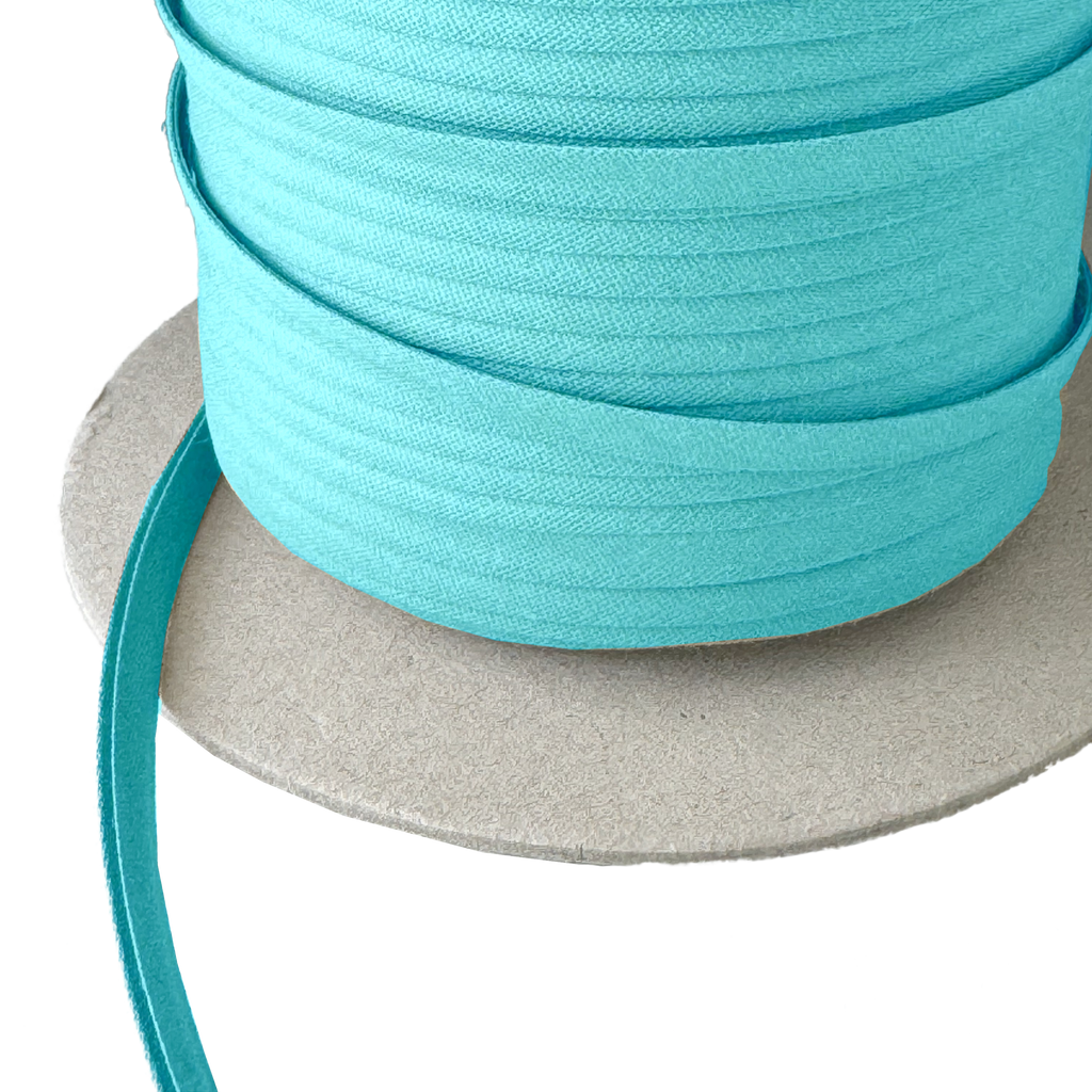 close up of the sky blue 1/4" double fold bias tape on a spool from Heit's Wholesale bulk sewing supply company