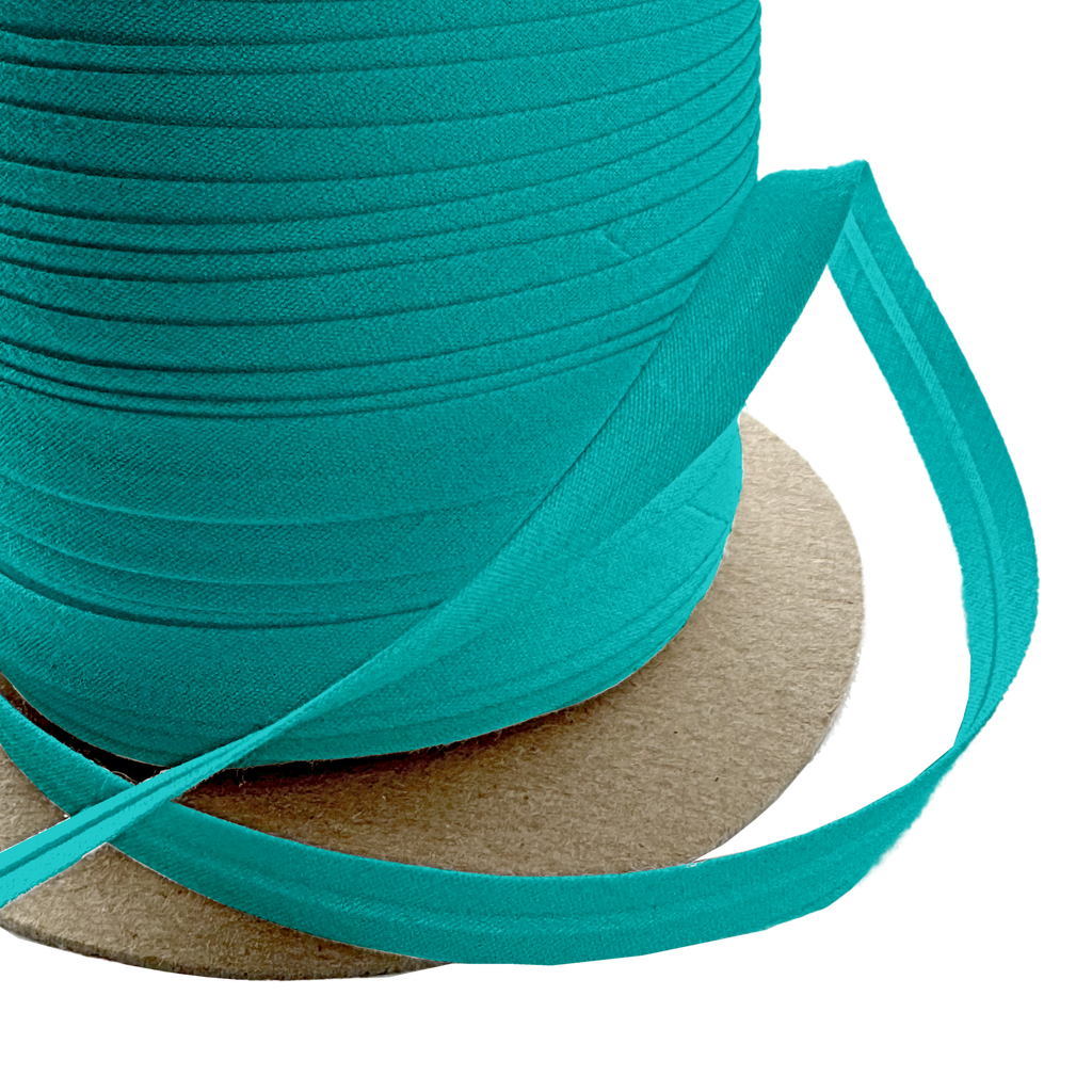 close up of the aquarius blue 3/8" single fold bias tape on a spool from Heit's Wholesale bulk sewing supply company