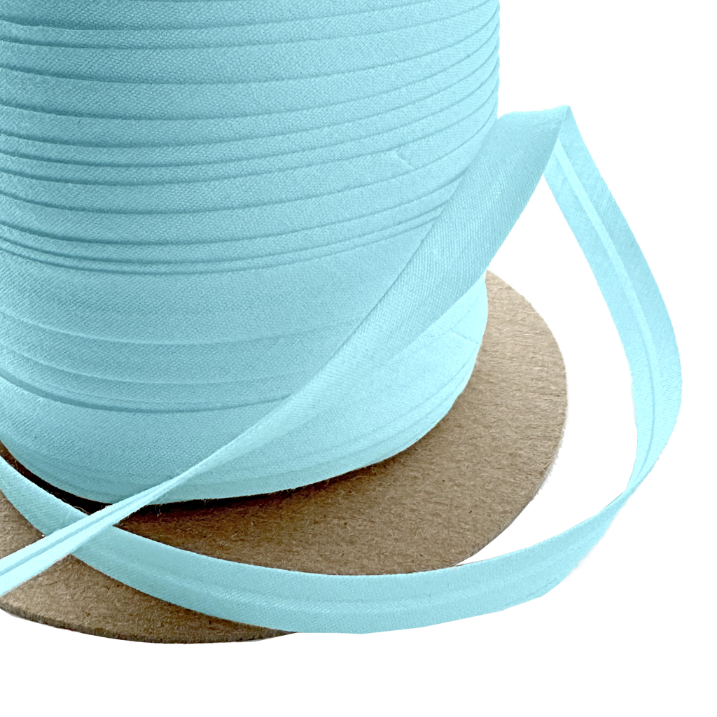 close up of the blue 3/8" single fold bias tape on a spool from Heit's Wholesale bulk sewing supply company