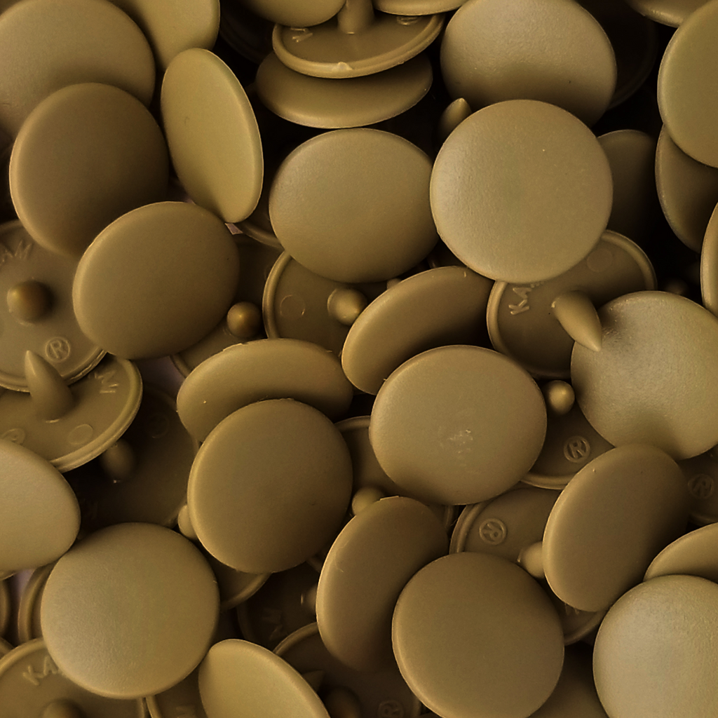 close up of the dark tan size 16 poly resin snaps for children's clothing sold at Heit's Wholesale bulks sewing supply company