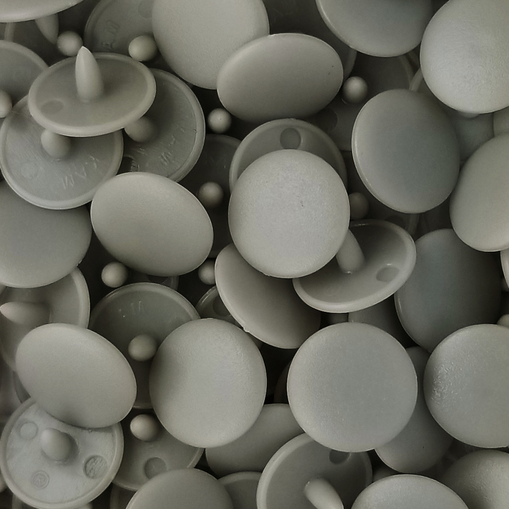 close up of the light gray size 16 poly resin snaps for children's clothing sold at Heit's Wholesale bulks sewing supply company