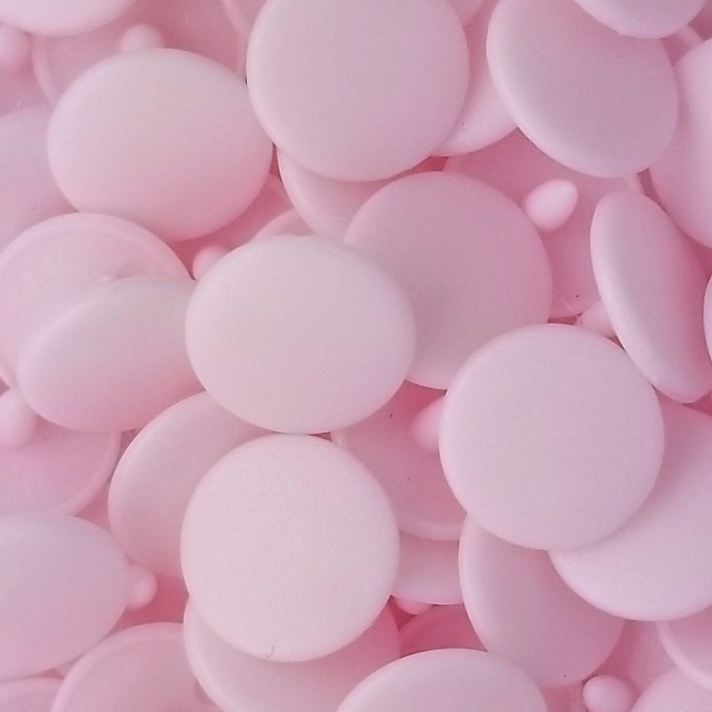 close up of the baby pink size 20 poly resin snaps with a matte finish from Heit's Wholesale bulk sewing supply company 