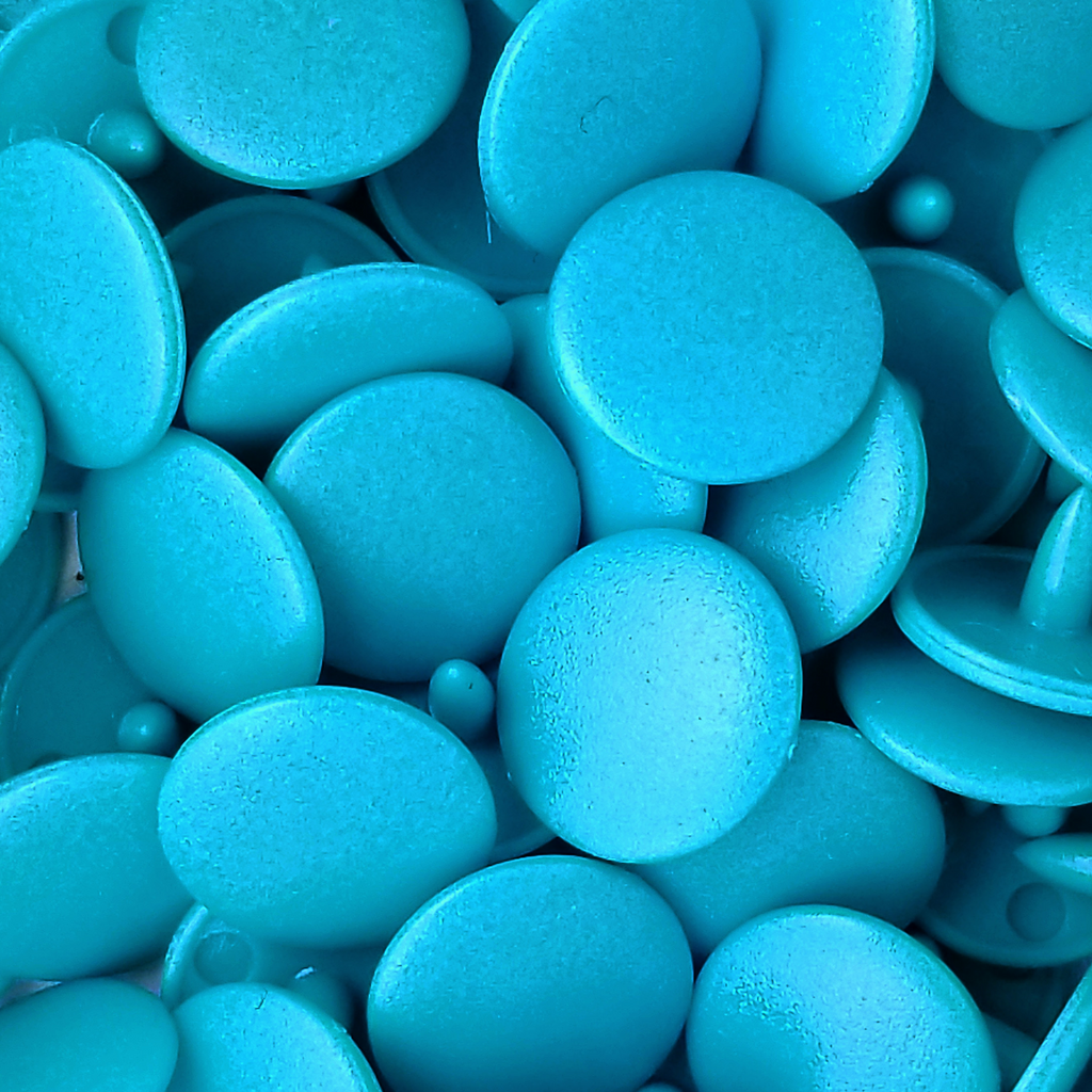 close up of the teal size 20 poly resin snaps with a matte finish from Heit's Wholesale bulk sewing supply company 