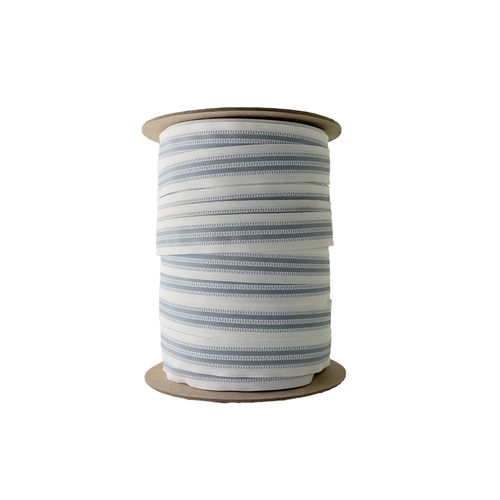 white and gray 1" snugtex waistband grip tape on a spool from Heit's Wholesale bulk sewing supply company